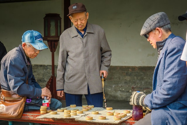 A few retirees playing chess at institutional care facility