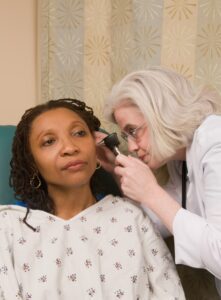 Audiologist uses otoscope to check patient's ears